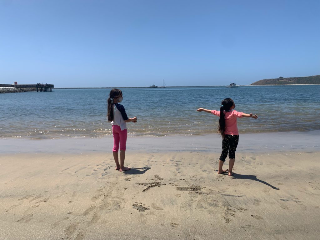 two girls stating on the sand at Pillar Point Beach in Half Moon Bay, California.