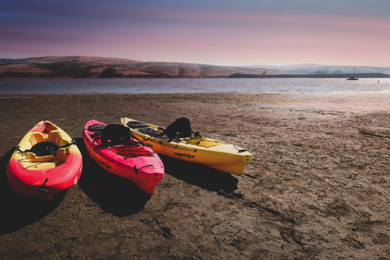 3 kayaks sitting on the short of Tomales Bay in California's Point Reyes national seashore.