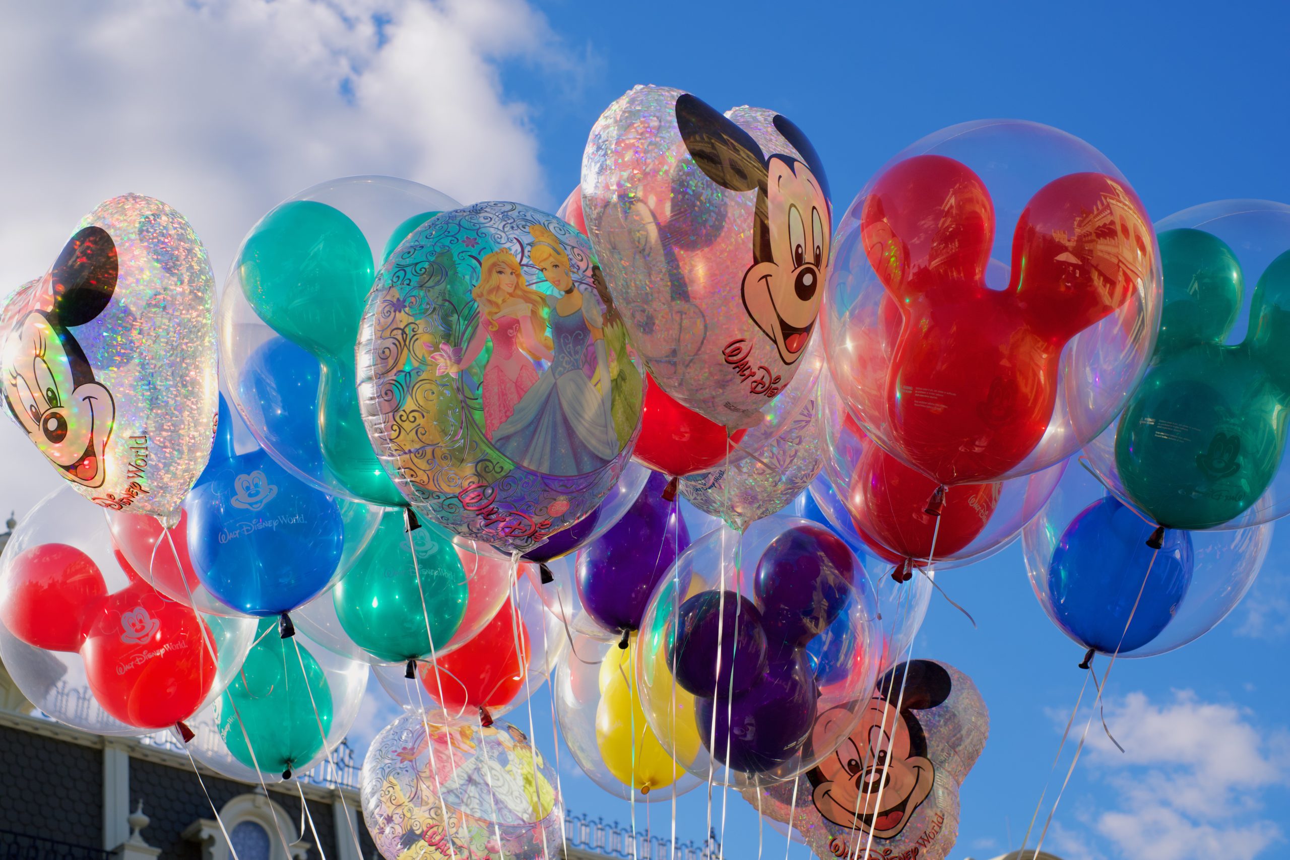 a bunch of colorful mickey mouse balloons floating in the air at disneyland