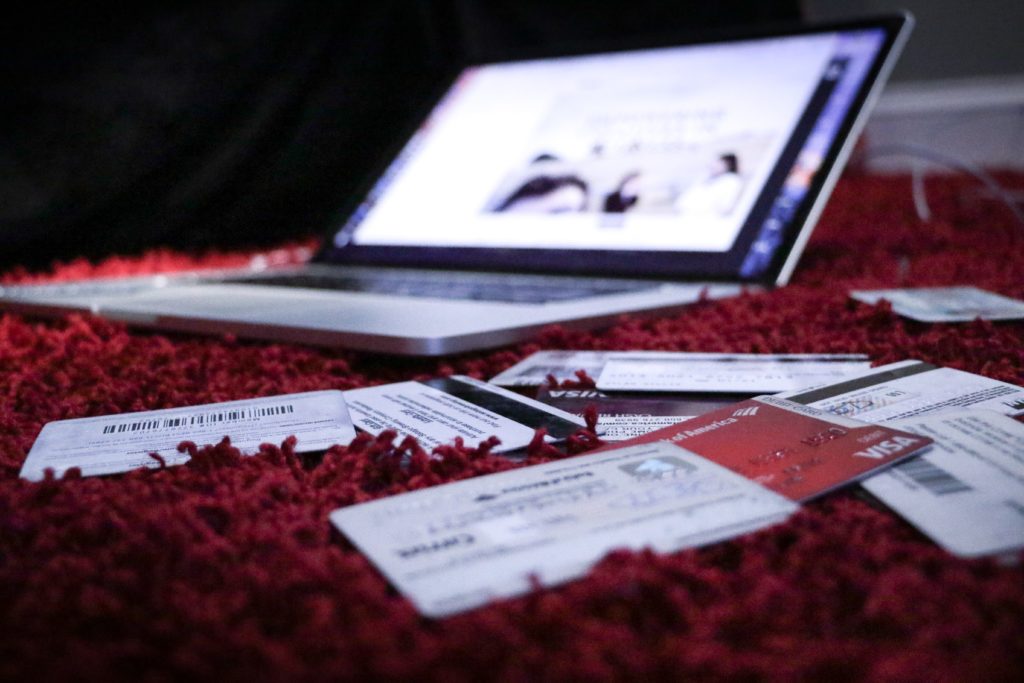 a pile of credit cards on a red rug and a laptop in the background