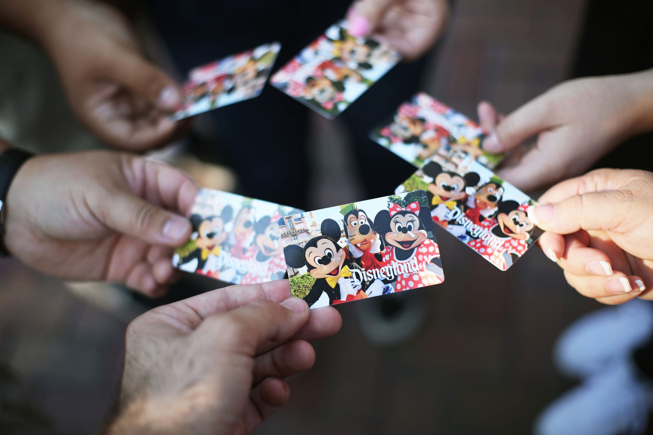 6 hands each holding a disneyland ticket