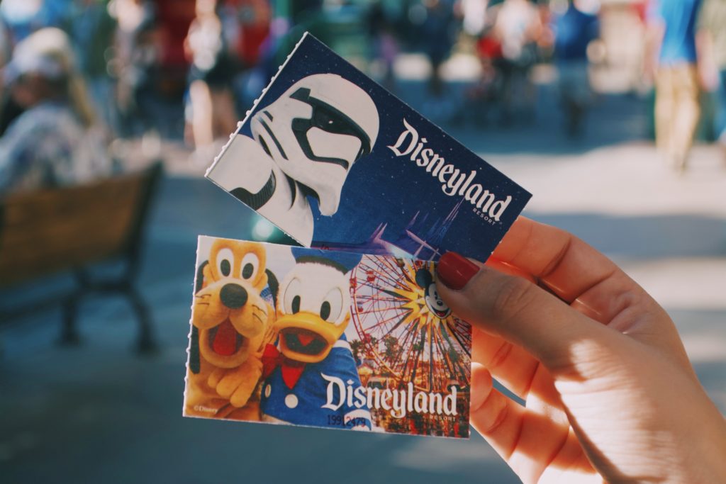 hands holding 2 disneyland tickets at disneyland