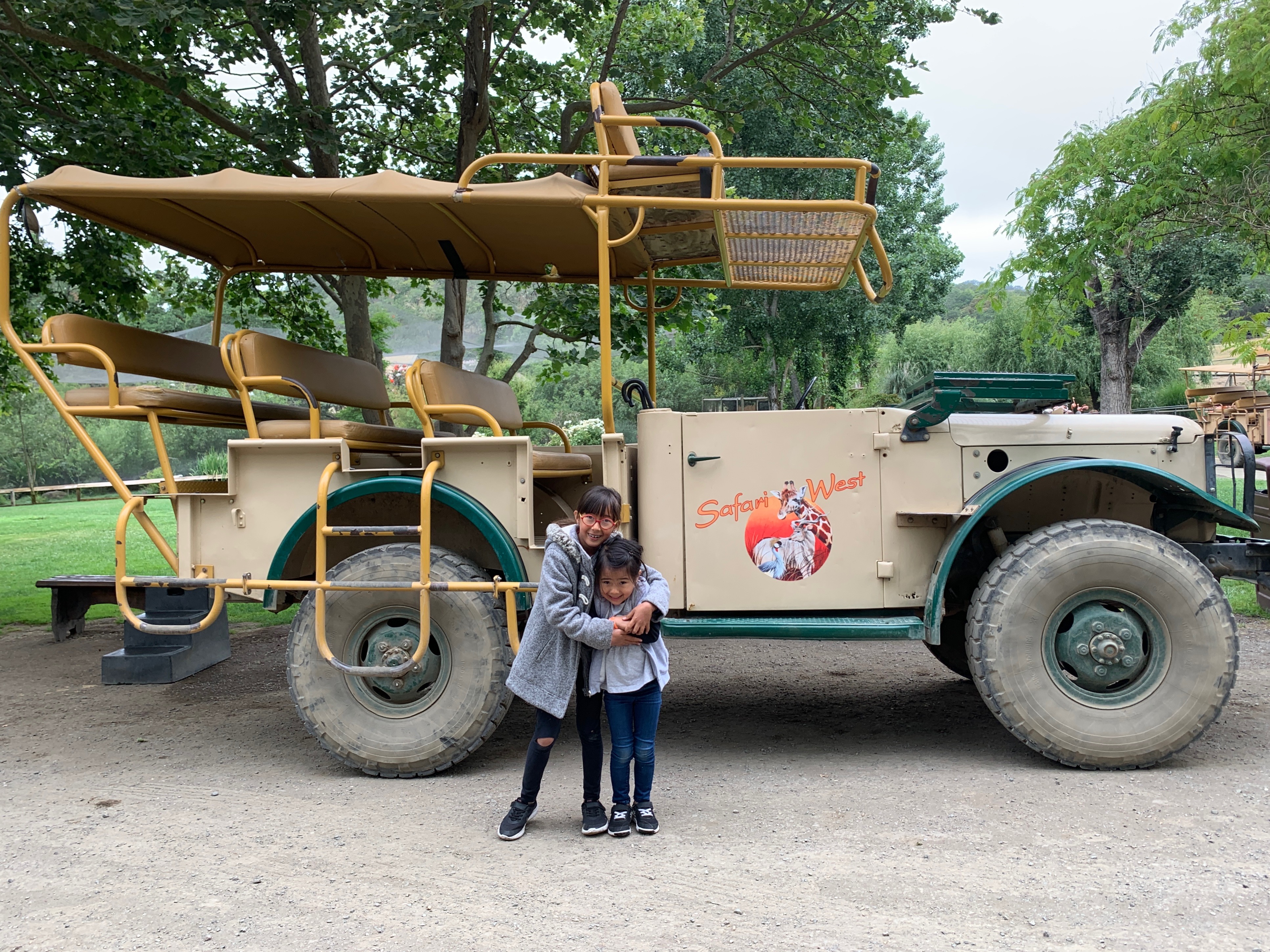 two girls standing in front of a jeep at Safari West