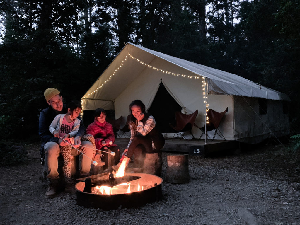 family roasting marshmallows with a tent in the background at Mendocino Grove, California