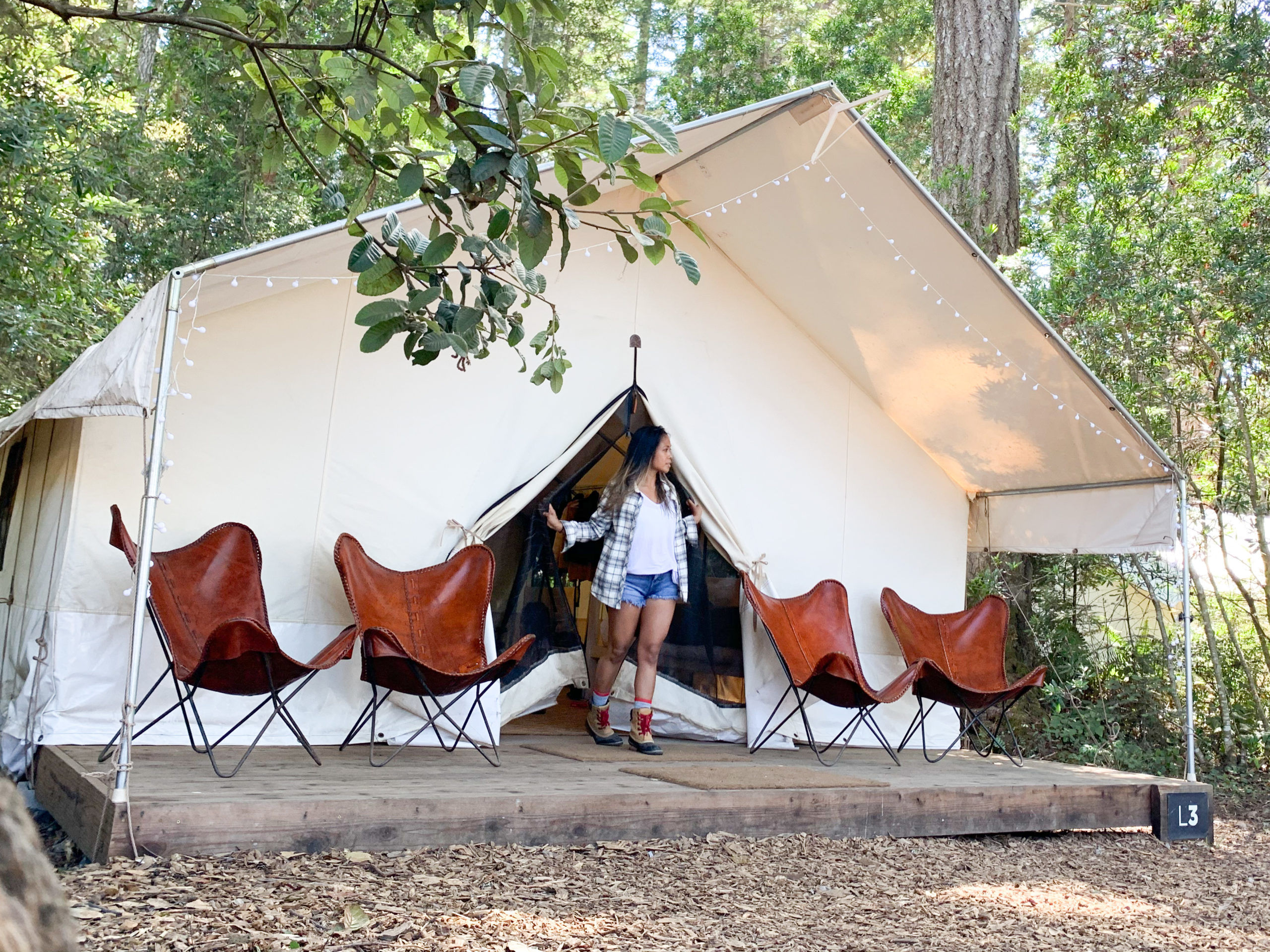 woman walking out of a gamping tent in Mendocino Grove, California