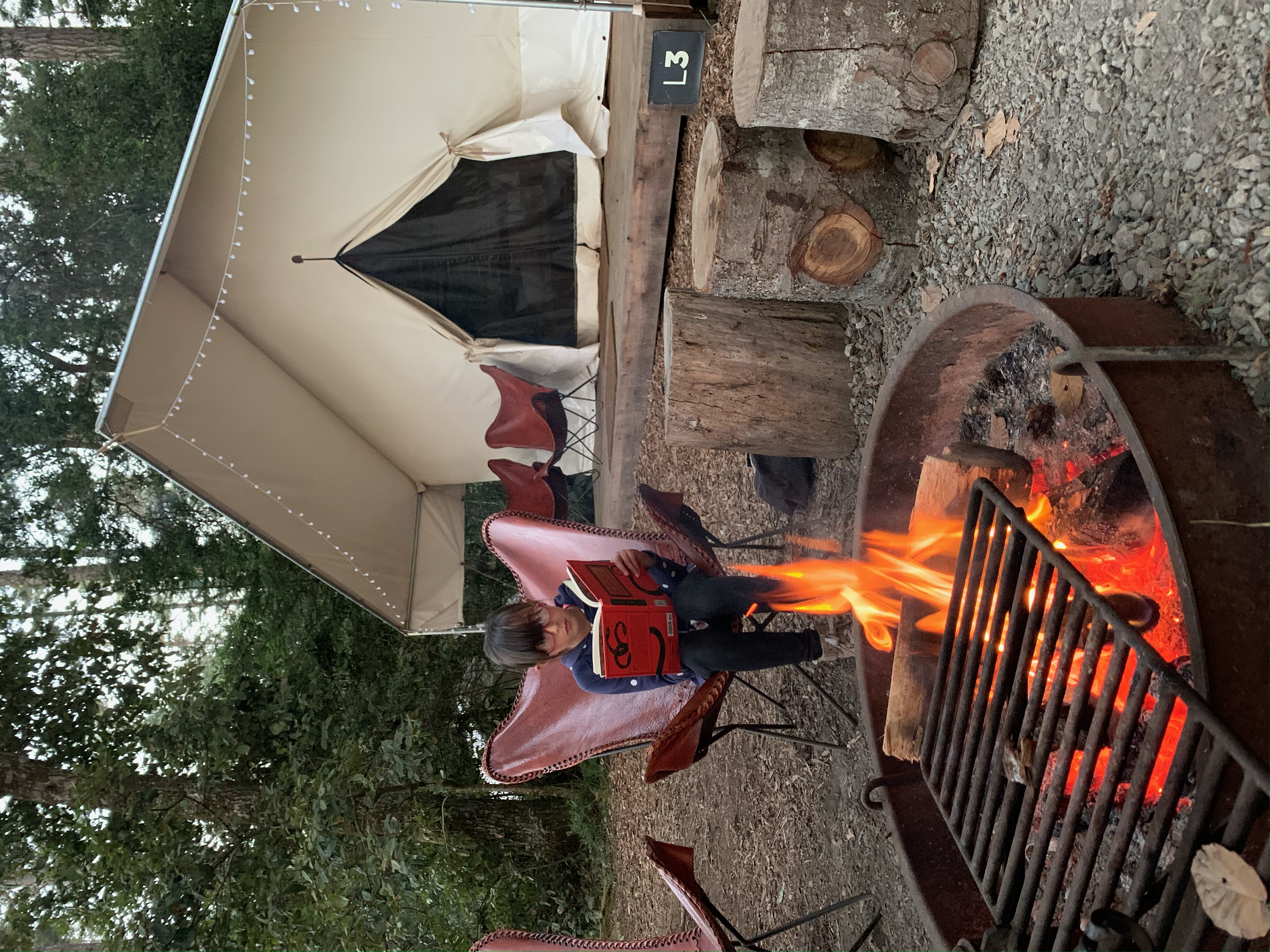 little girl reading a book by a fire at Mendocino Grove California