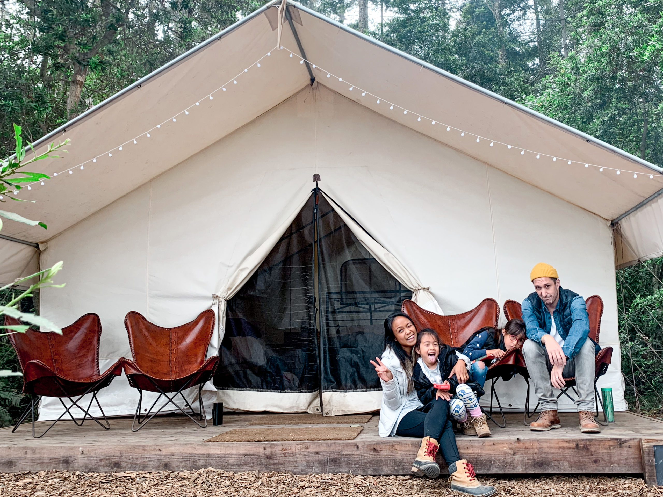 a family of four sitting in front of a glamping tent at Mendocino Grove in Mendocino California