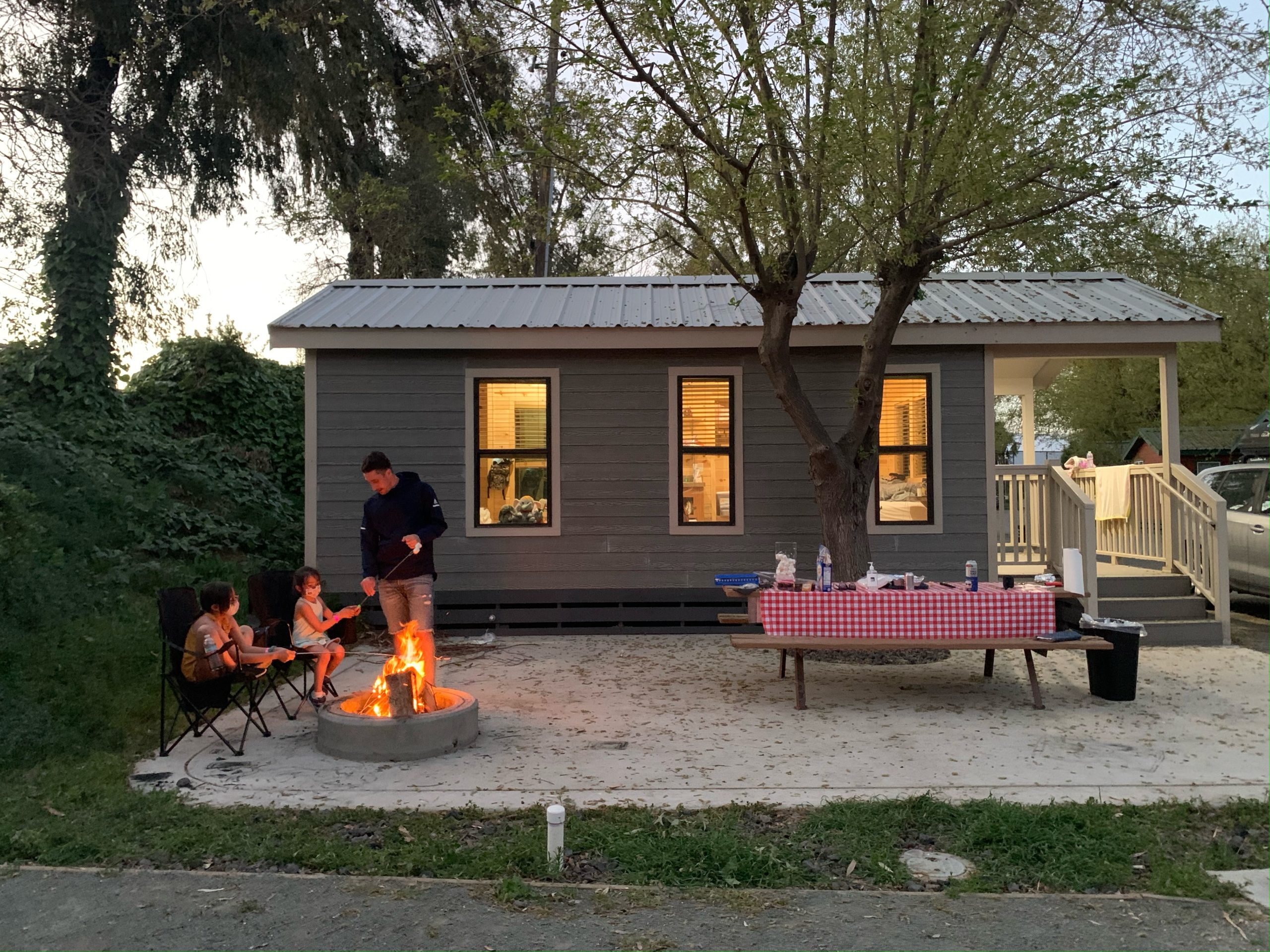 family sitting around a camp fire in front of a cabin at Yogi Bear Camp in Lodi California