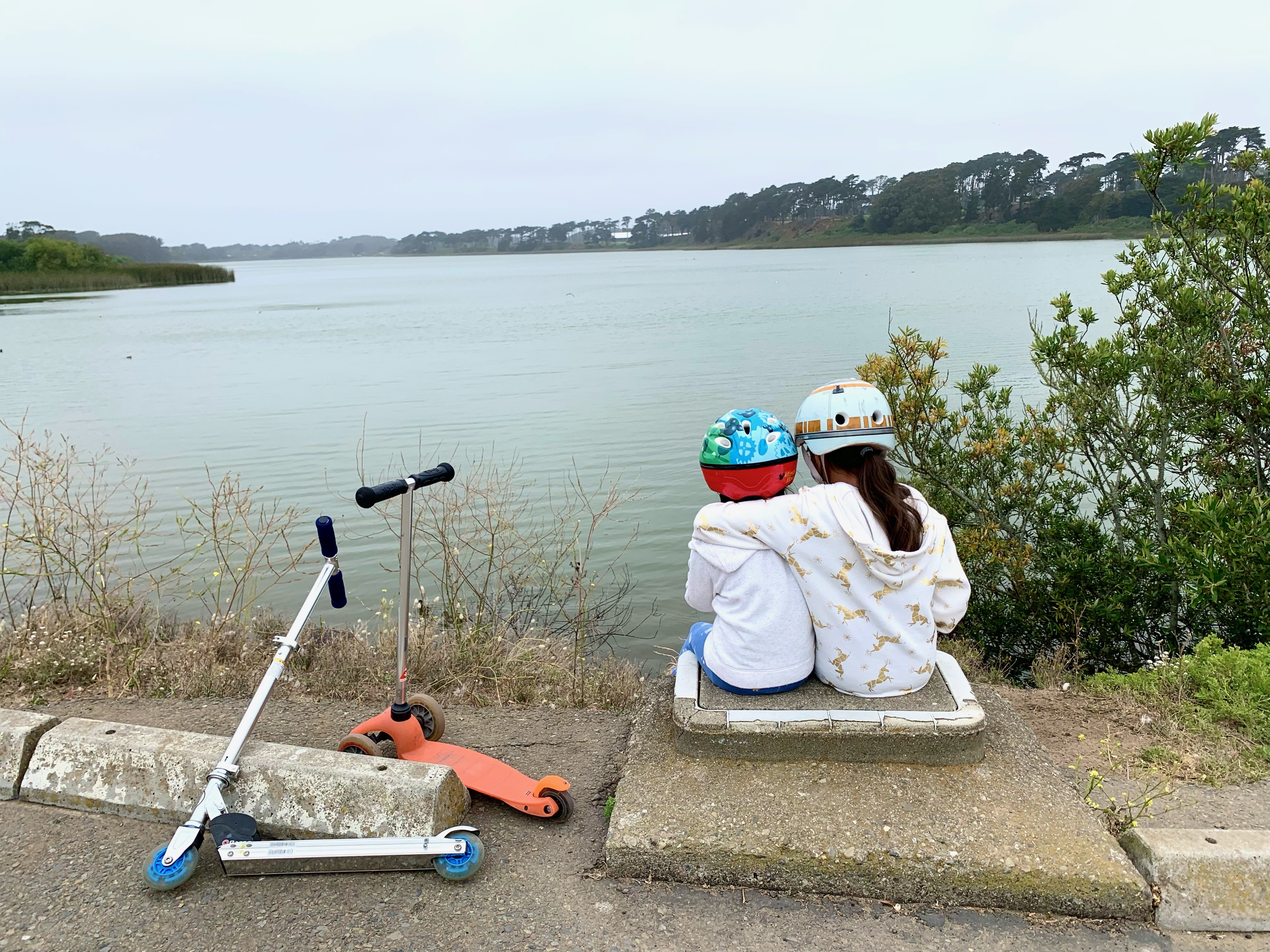 two girls wearing helmets sitting at Lake Merced in San Francisco