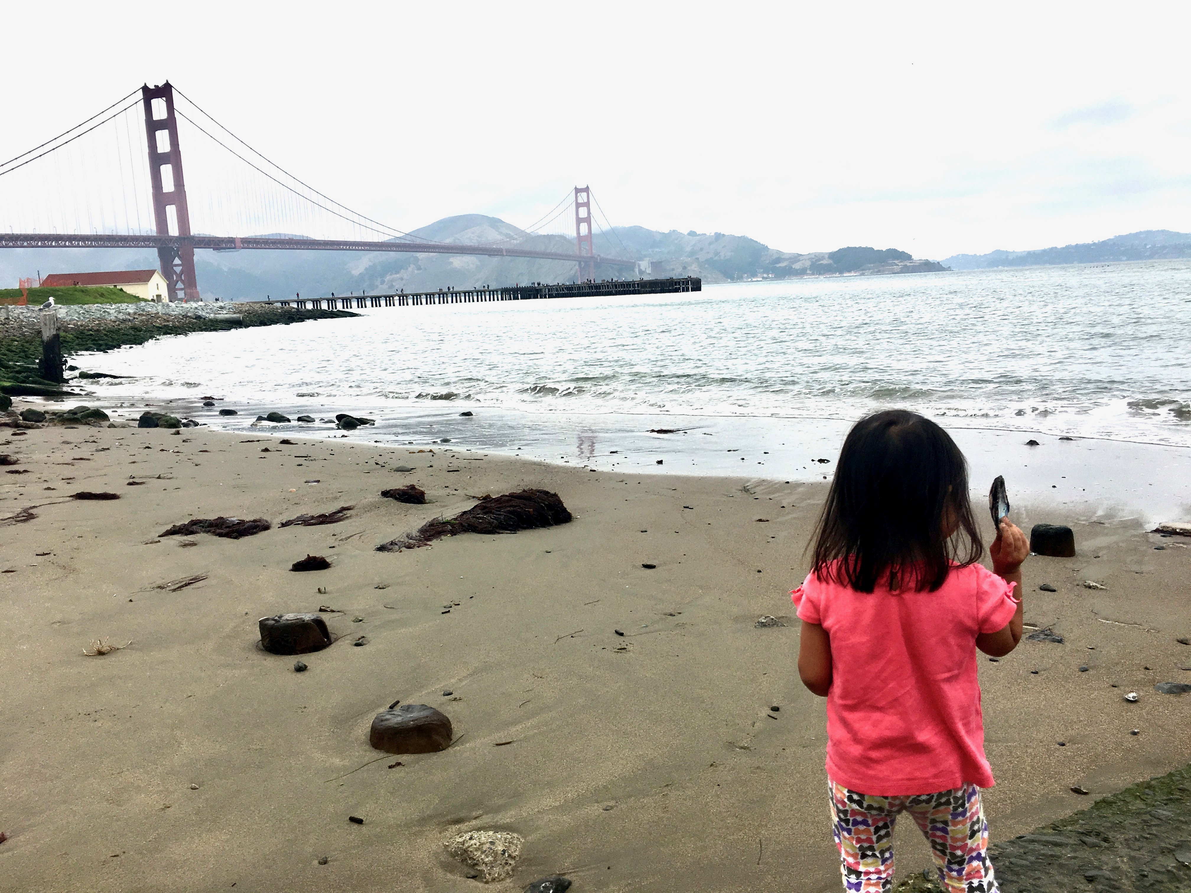 little girl at the beach in front of the golden gate bridge