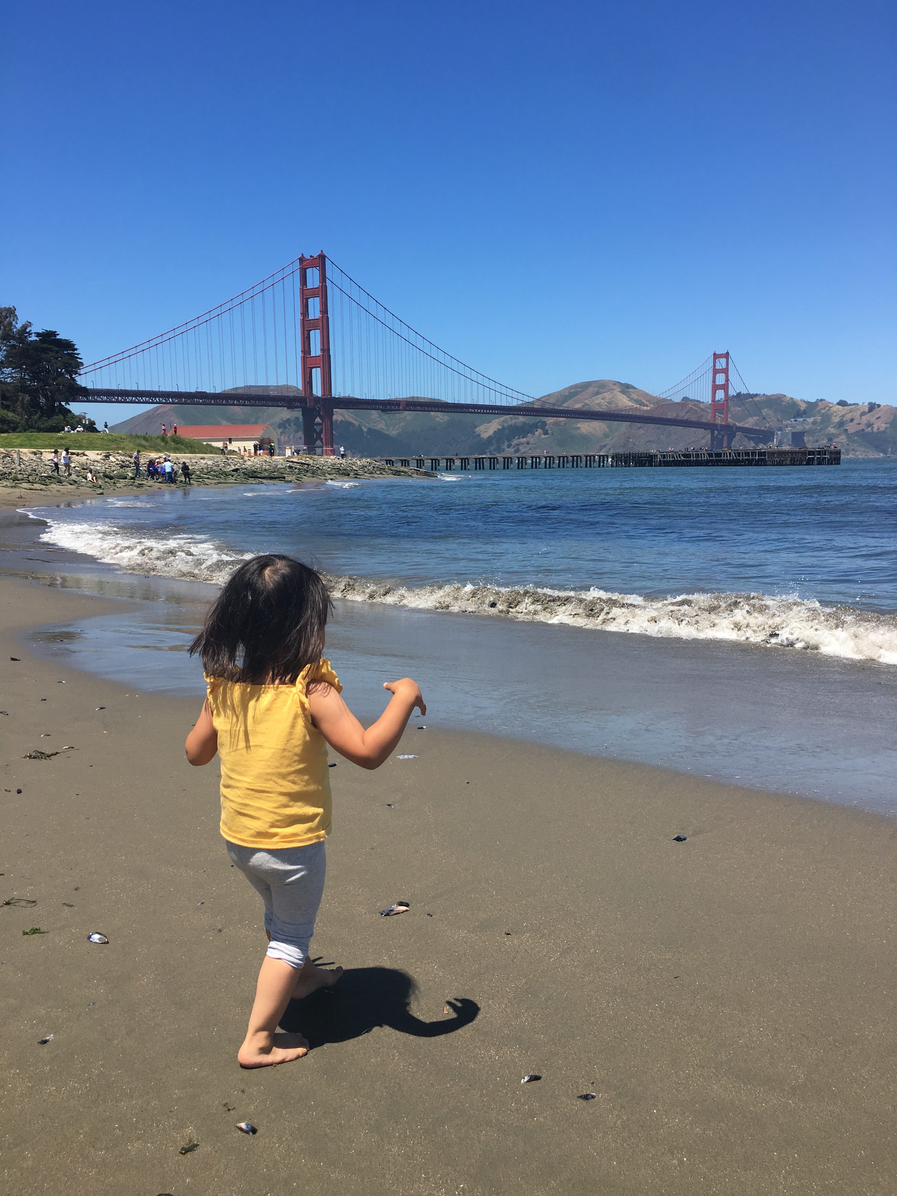 girl playing at West Bluff picnic area with the Golden Gate Bridge in the back ground in San Francisco, California