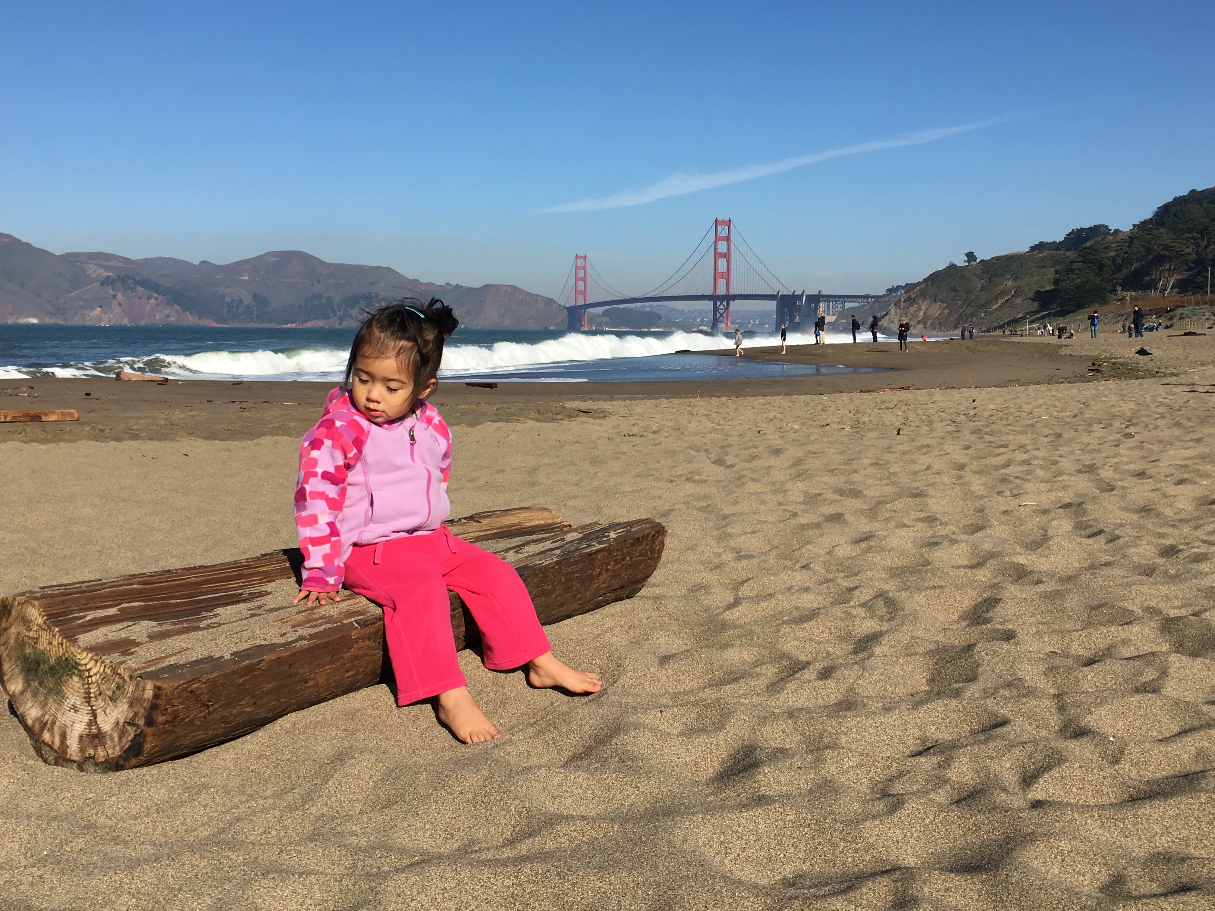 little girl sitting on a log at Baker Beach San Francsico