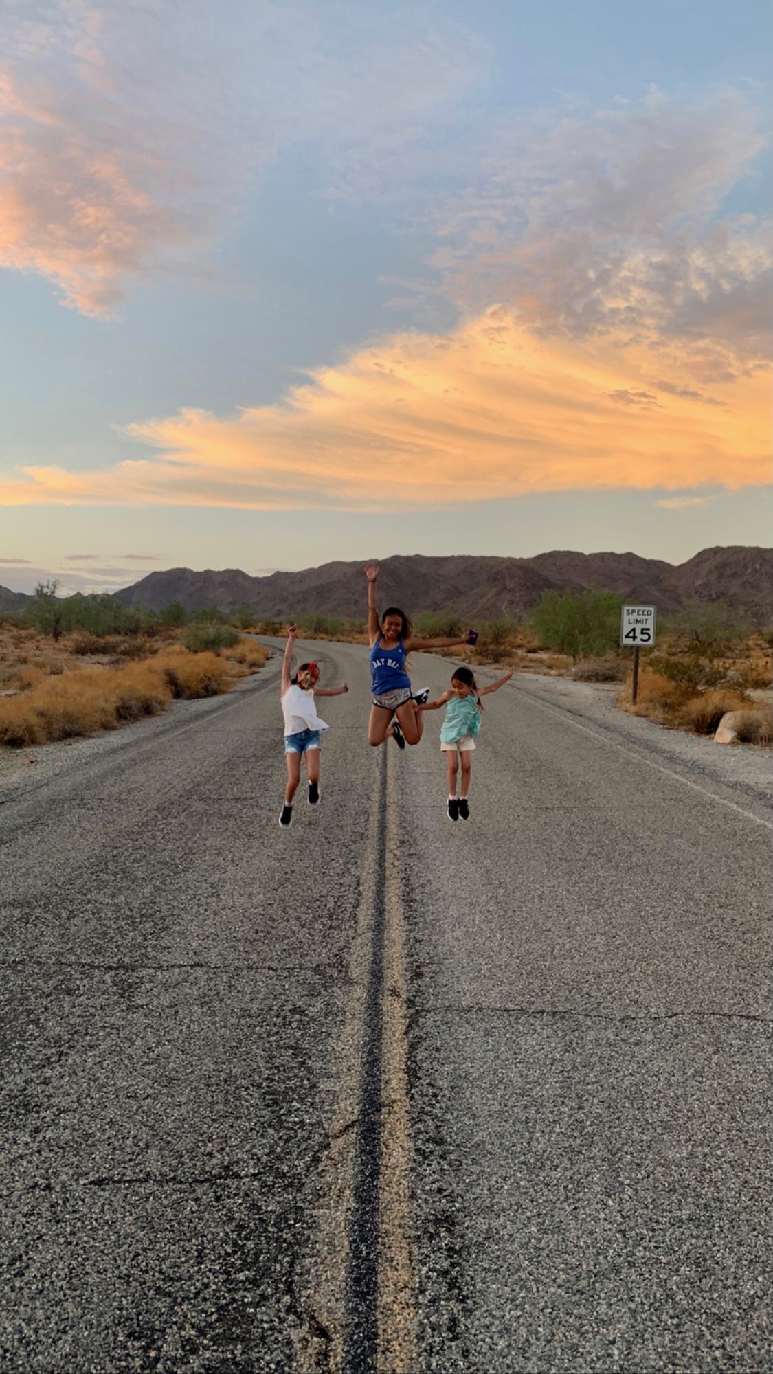 kids and mom jumping in the middle of a road in Joshua Tree