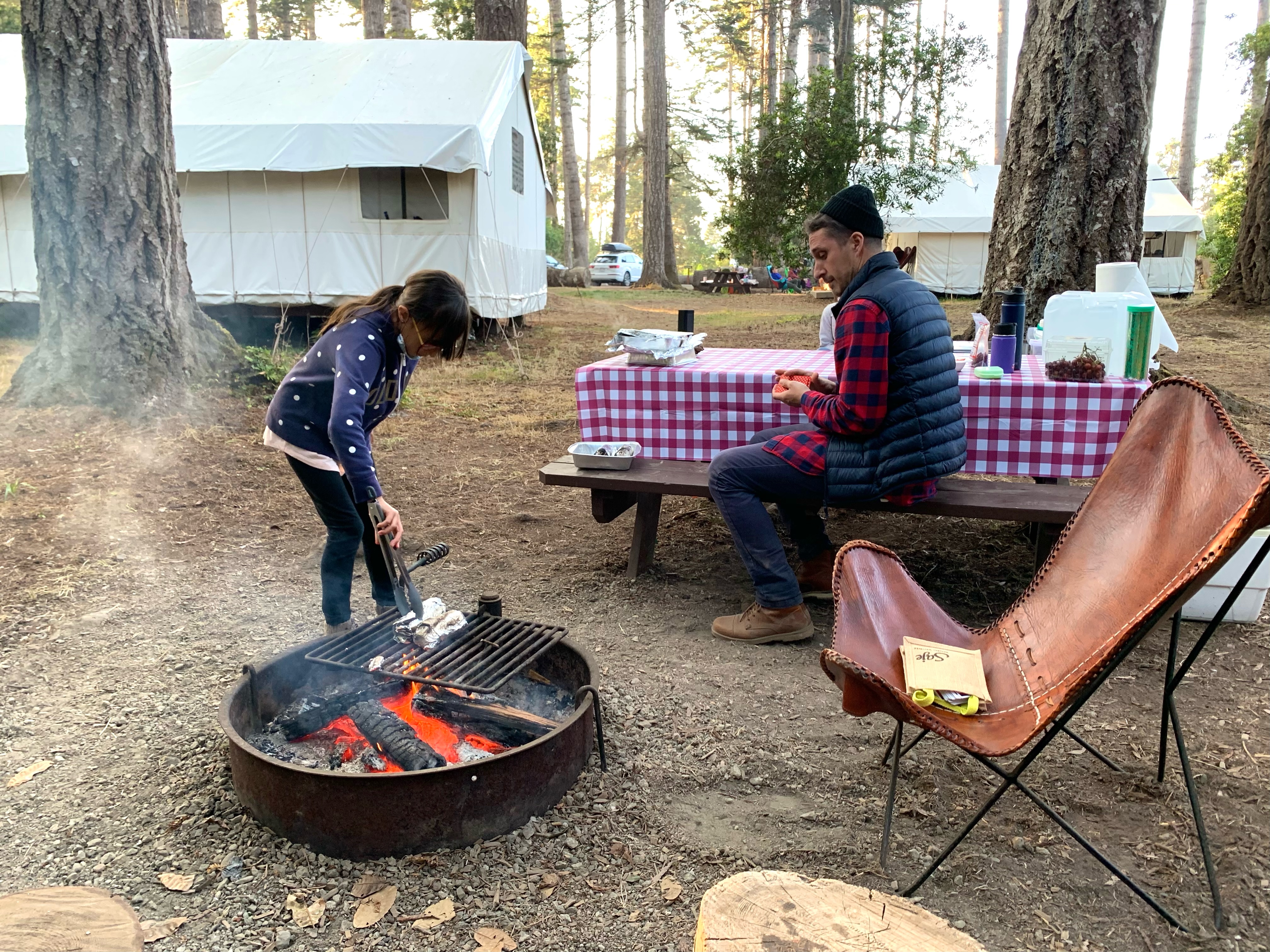 girl cooking dinner over a camp fire at mendocino grove, california