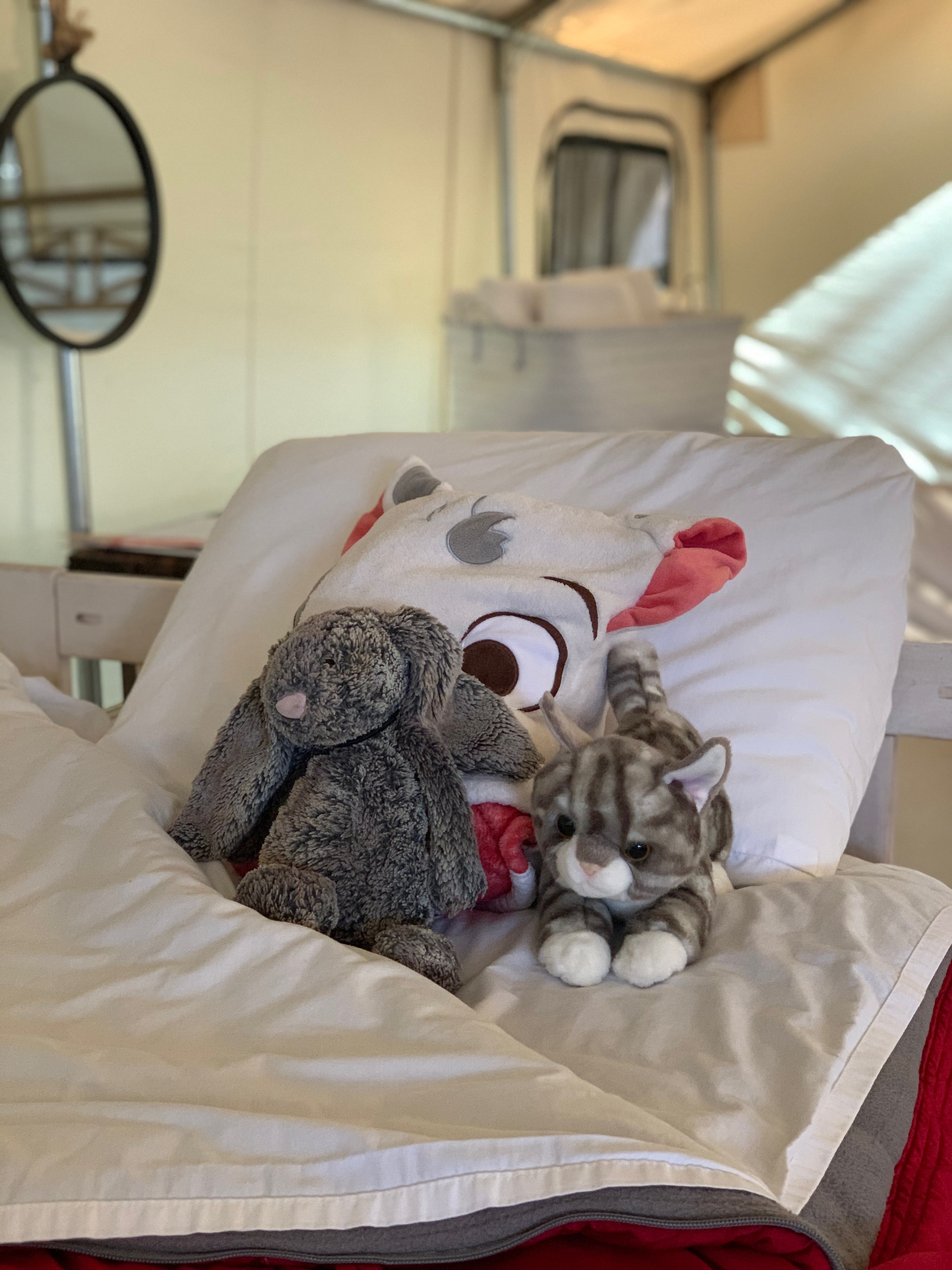 stuffed animals on a bed in a safari tent