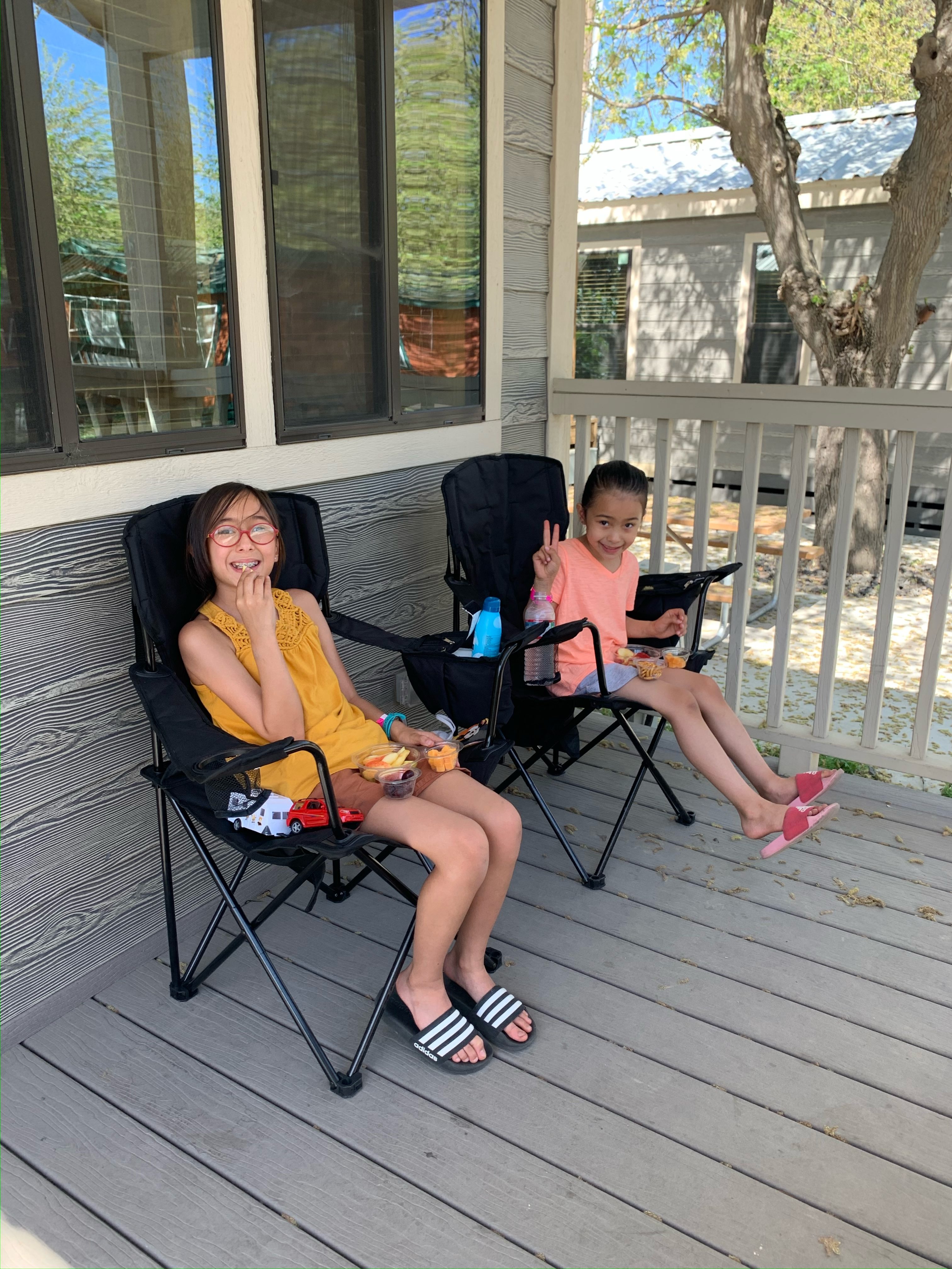 two girls sitting on the porch of a cabin at Jellystone Park Lodi, California